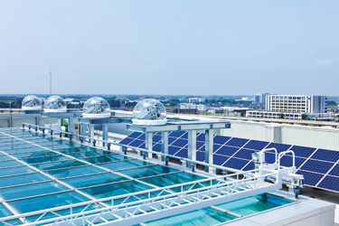 屋上に設置したソーラーパネルと半球型の太陽光自動追尾装置。自然光を屋内に取り込む（画像：理想科学工業）