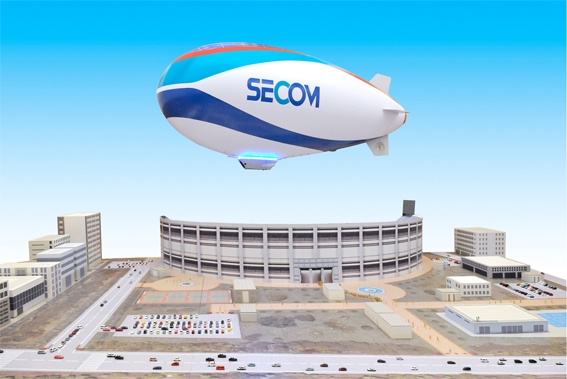 1/50の都市ジオラマの上に浮く1/3スケールの「セコム飛行船」(セコムの発表資料より)