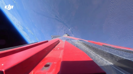 ロケットの赤いフィン越しに機体後方を捉えた搭載カメラの映像。上昇する機体の背後に、宇宙の暗闇と地球の丸みが浮かび上がる (Dji.com) ロケットの赤いフィン越しに機体後方を捉えた搭載カメラの映像。上昇する機体の背後に、宇宙の暗闇と地球の丸みが浮かび上がる (Dji.com)